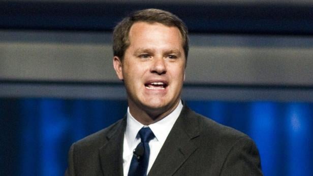 Ein Mann in Anzug und Krawatte spricht vor einem Publikum.