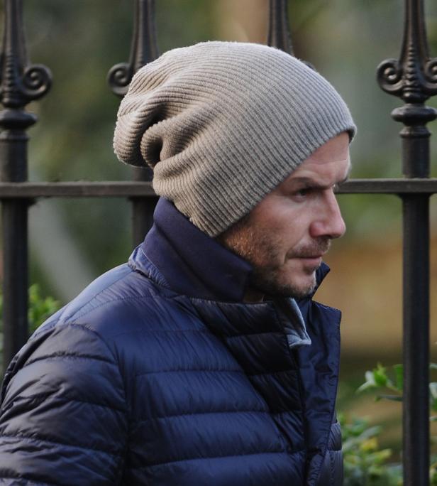 David Beckham mit Mütze und blauer Jacke im Profil.