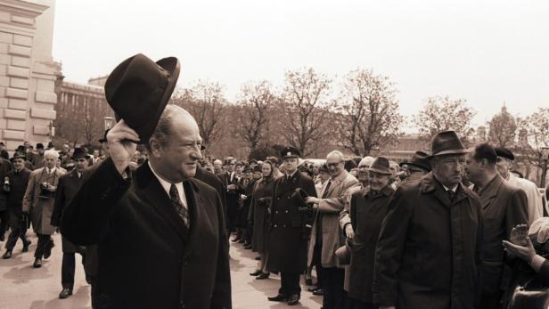 Ein Mann mit Hut grüßt eine Menschenmenge.