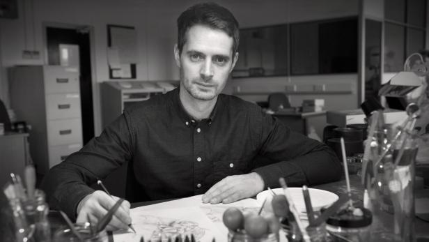 Ein Mann zeichnet in einem Büro mit Stift auf Papier.