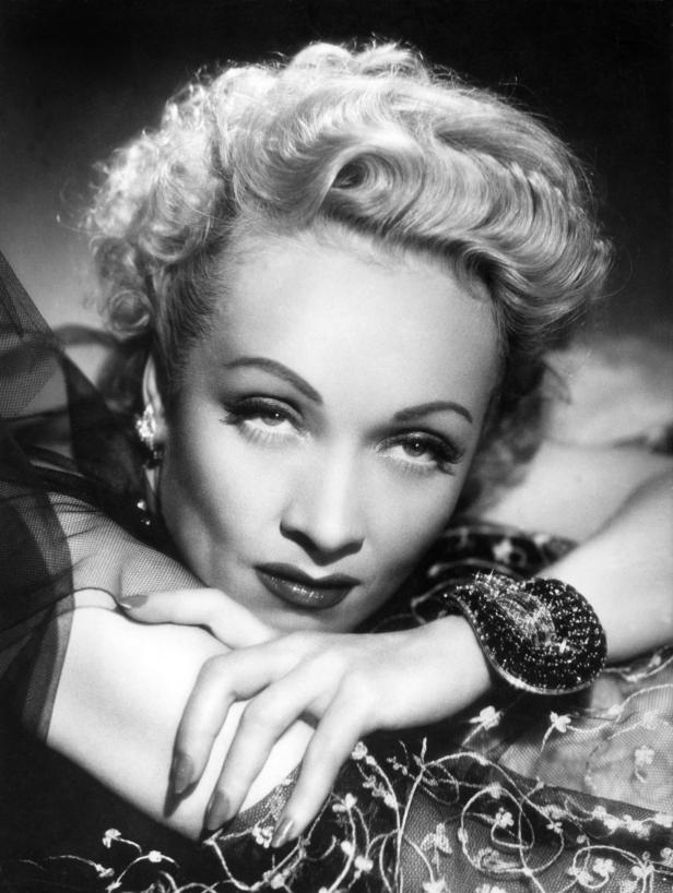 Ein Schwarzweißporträt von Marlene Dietrich mit kunstvoll hochgestecktem Haar.