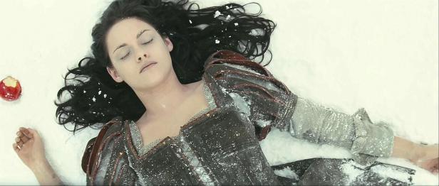 Eine Frau mit dunklen Haaren liegt bewusstlos im Schnee, neben ihr ein angebissener Apfel.