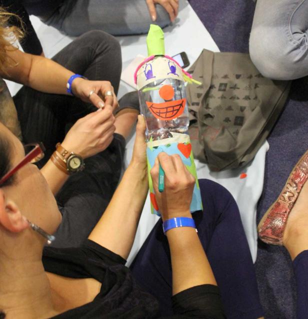 Eine Gruppe von Menschen bastelt eine Figur aus einer Plastikwasserflasche.