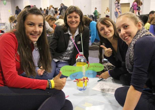 Eine Gruppe junger Frauen sitzt auf dem Boden und bastelt an einem Projekt mit dem Titel „Different But Not Indifferent“.