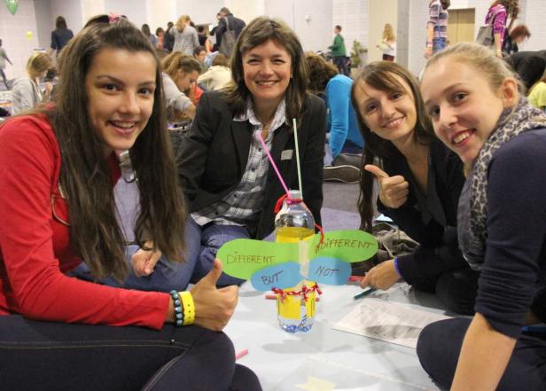 Eine Gruppe von Frauen sitzt um ein Projekt mit der Aufschrift „Different but not indifferent“.