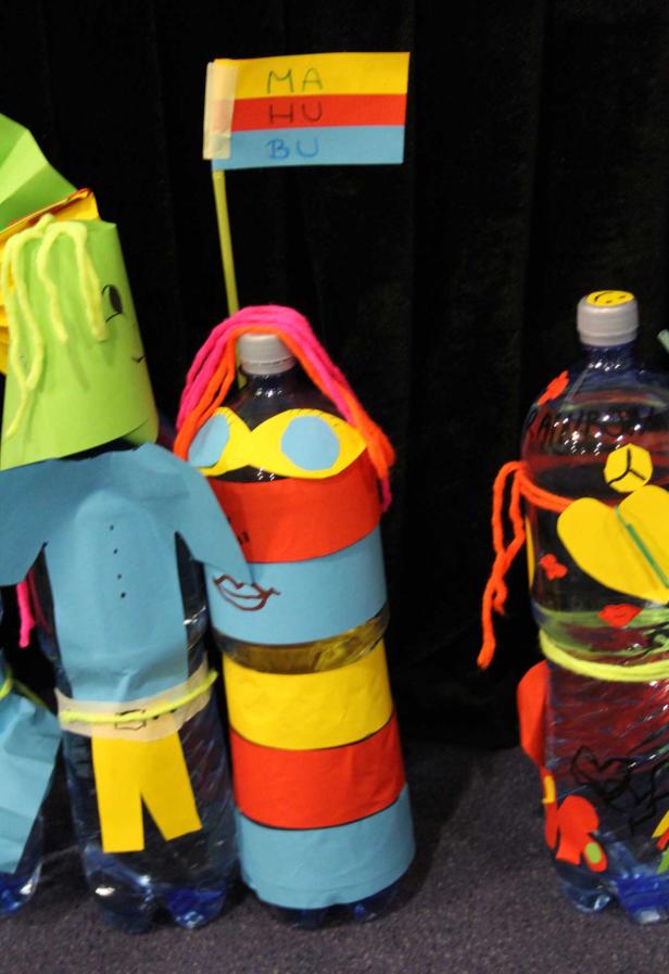 Kreative, recycelte Figuren aus Plastikflaschen und Papier, mit einem Schild „MA HU BU“.