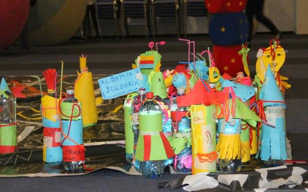 Kreative, bunte Kunstprojekte aus Plastikflaschen und Papier stehen auf einem Tisch.