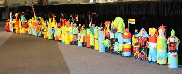 Eine Reihe bunter, dekorierter Plastikflaschen steht auf dem Boden.