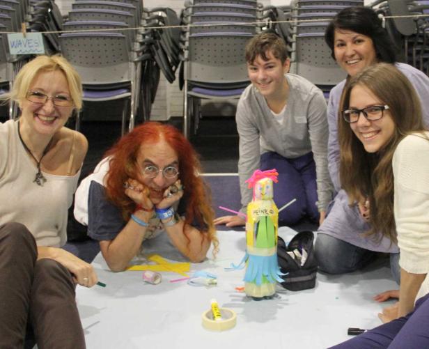 Eine Gruppe von Personen sitzt um eine selbstgebastelte Figur und bastelt gemeinsam.