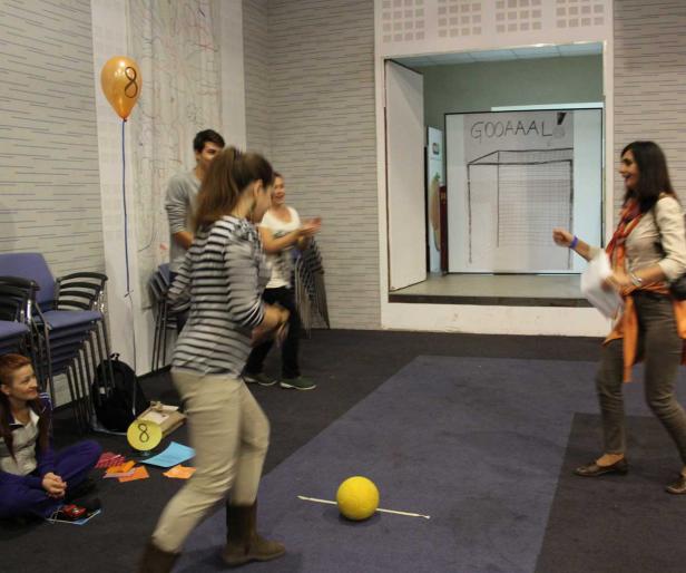 Eine Frau schießt einen gelben Ball in Richtung eines auf eine Tür gemalten Tores.