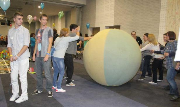 Eine Gruppe von Menschen schiebt einen riesigen, zweifarbigen Ball.