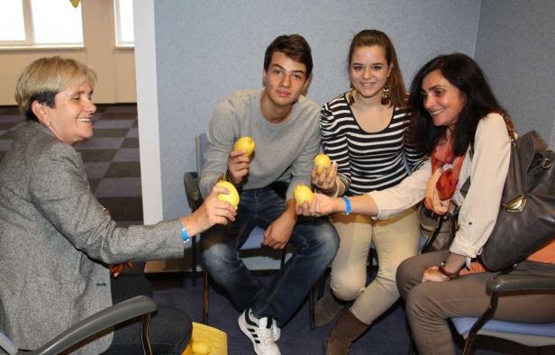 Eine Gruppe von vier Personen sitzt auf Stühlen und hält Zitronen in den Händen.