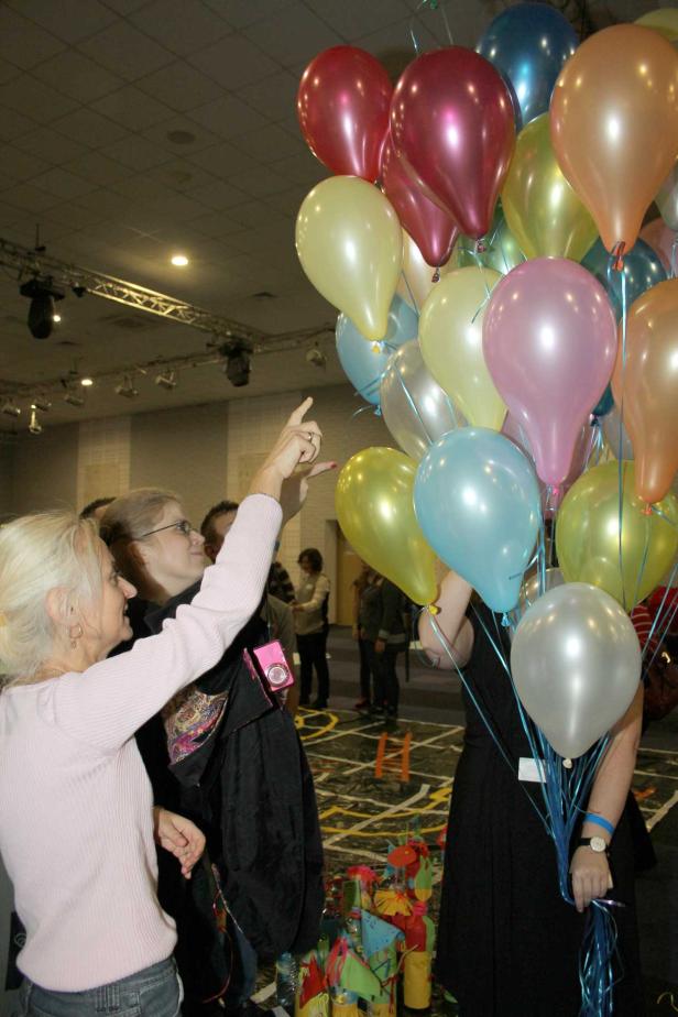 Frauen stehen mit einem Bündel bunter Ballons in einem Raum.