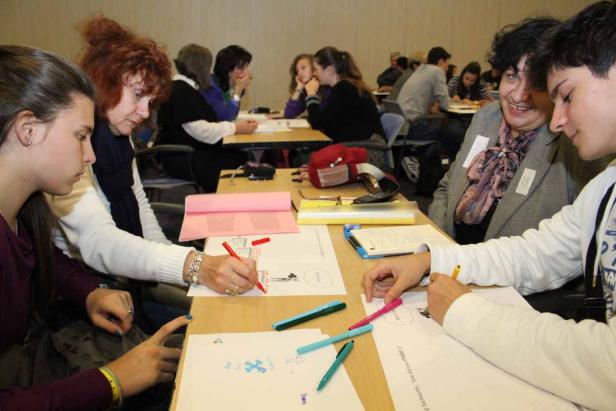 Mehrere Personen sitzen an Tischen und arbeiten an ihren Aufgaben.