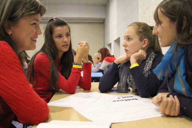 Vier Frauen sitzen an einem Tisch und diskutieren über ein Blatt Papier.