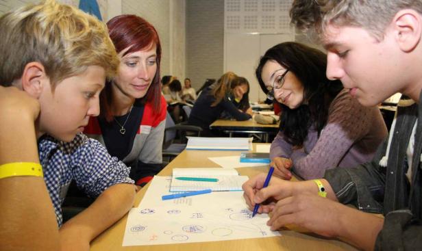 Schüler und Lehrer arbeiten gemeinsam an einem Projekt mit Zeichnungen.