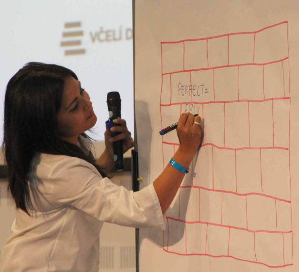 Eine Frau schreibt mit einem Stift auf ein Whiteboard, auf dem ein Raster gezeichnet ist.