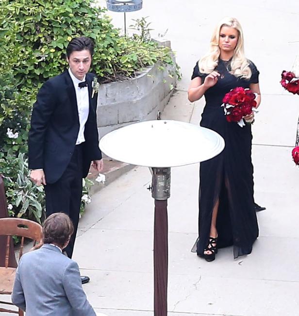 Jessica Simpson in einem schwarzen Kleid mit einem roten Blumenstrauß bei einer Veranstaltung.