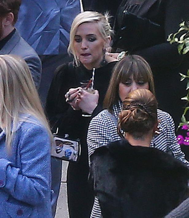 Eine blonde Frau hält ein Getränk mit Strohhalm in der Hand.