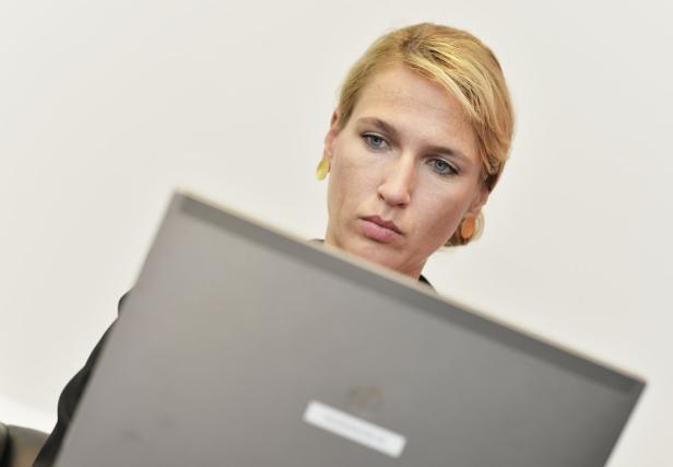 Eine Frau mit blonden Haaren schaut aufmerksam auf einen Laptop.