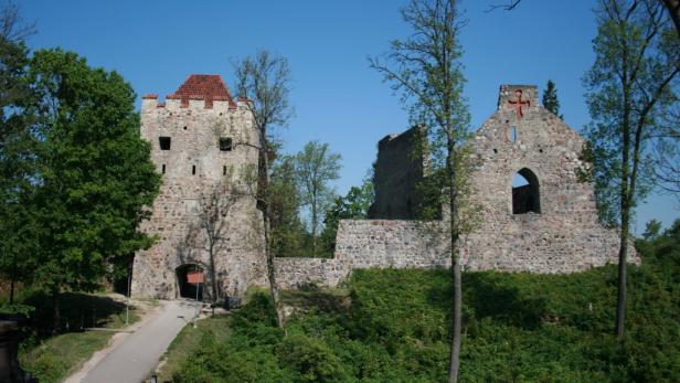 Die Ruine einer alten Burg mit einem Turm und einer roten Kreuzverzierung.