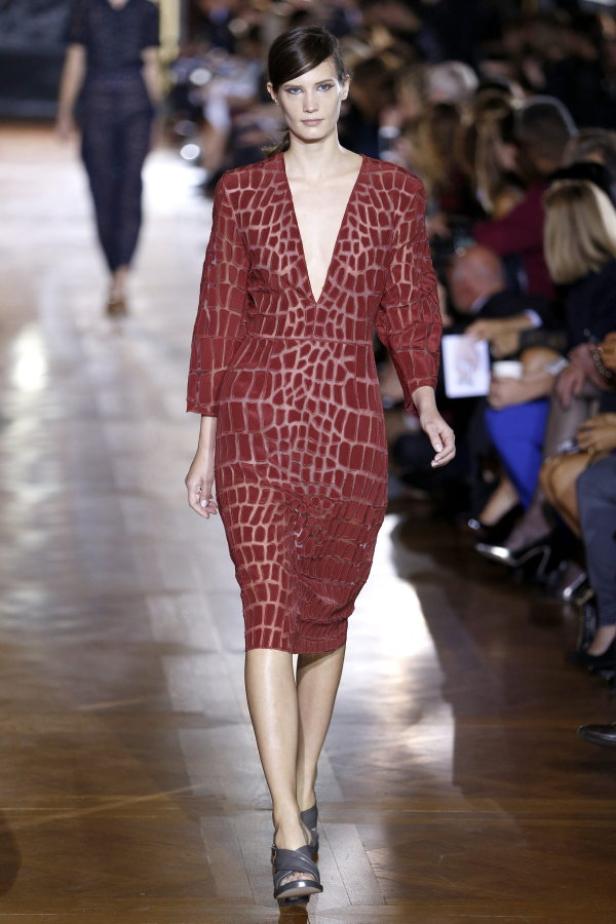 Eine Frau präsentiert ein rotes Kleid mit geometrischem Muster auf einem Laufsteg.