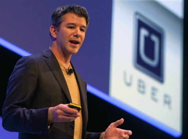 Ein Mann hält ein Gerät in der Hand und spricht vor einem Uber-Logo.