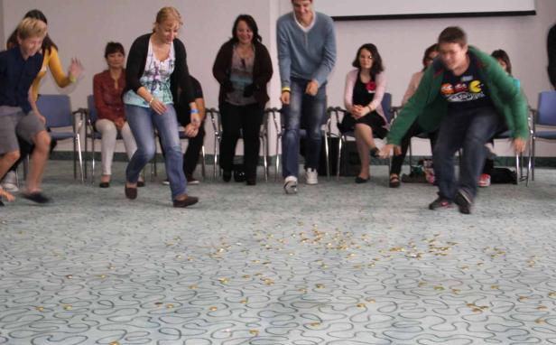 Eine Gruppe von Menschen spielt ein Spiel mit Münzen auf dem Boden.