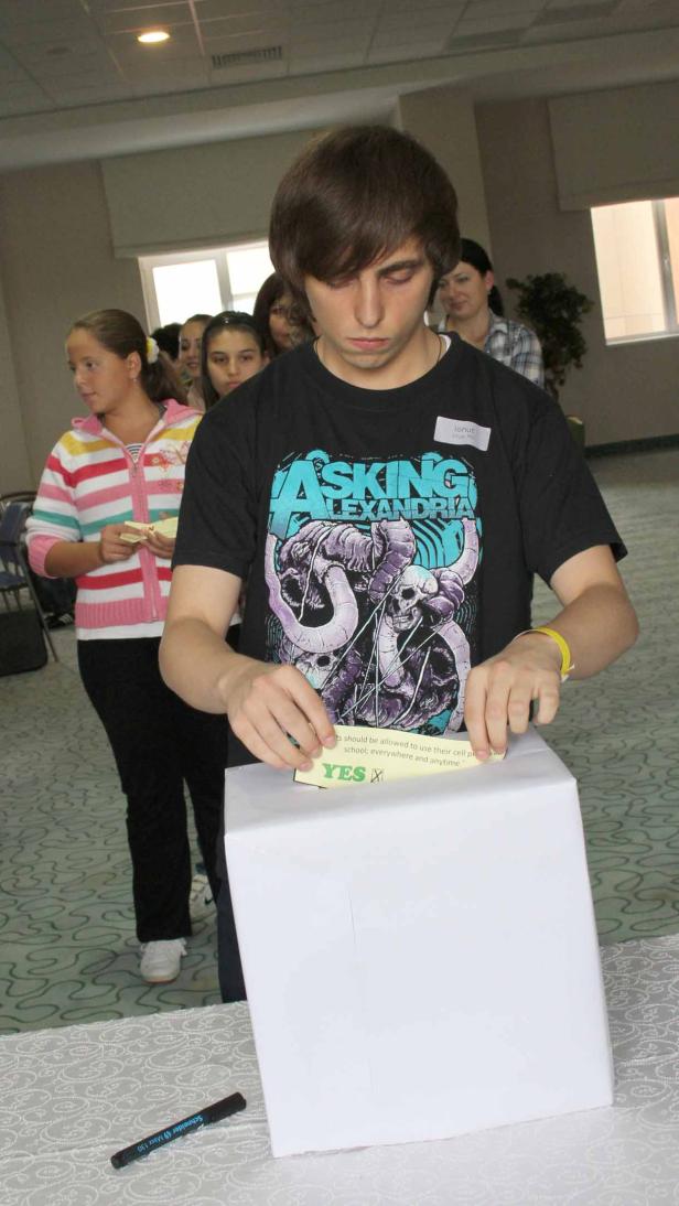 Ein junger Mann wirft einen Zettel mit einem „Ja“-Kreuz in eine weiße Wahlurne.