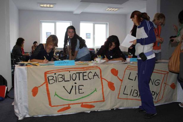 Mehrere Frauen sitzen an einem Tisch mit der Aufschrift „Biblioteca Vie Library“.