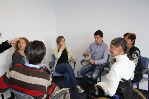 Eine Gruppe von Menschen sitzt in einem Kreis und diskutiert.