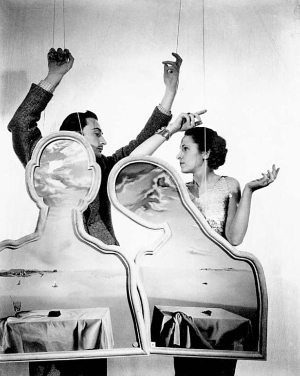 Salvador Dalí und Gala posieren mit surrealen Gemälden in Form von Köpfen.