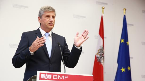 Ein Mann in Anzug gestikuliert vor der österreichischen und der EU-Flagge.