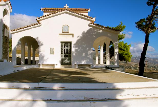 Eine kleine, weiße Kirche mit einem Kreuz auf dem Dach unter blauem Himmel.