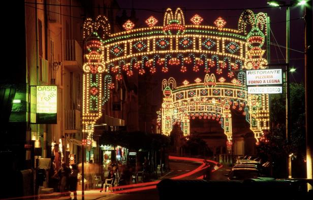 Eine italienische Stadtstraße ist nachts mit festlichen Lichtern geschmückt.