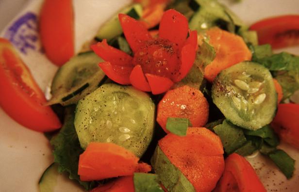 Ein frischer Salat mit Tomaten, Gurken und Karotten auf einem Teller.