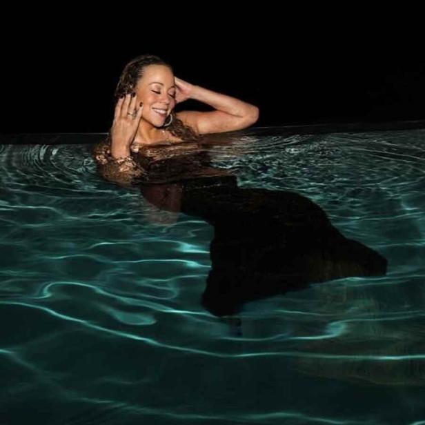Mariah Carey posiert in einem schwarzen Kleid im Wasser.