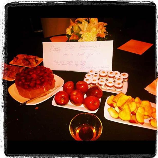Ein Tisch gedeckt mit Speisen für Rosch Haschana, darunter Äpfel, Honig und Kuchen.