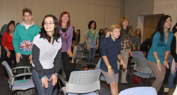Eine Gruppe von Menschen steht in einem Raum und macht Dehnübungen.