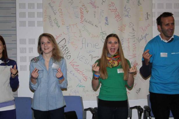 Eine Gruppe von Personen steht vor einer Wand mit vielen Namen darauf.