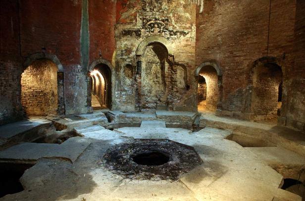 Ein unterirdischer Raum mit einem Loch in der Mitte und mehreren gewölbten Durchgängen.