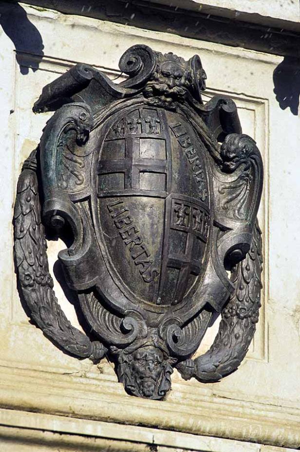 Ein verziertes Wappen mit der Inschrift „Libertas“ an einer Wand.