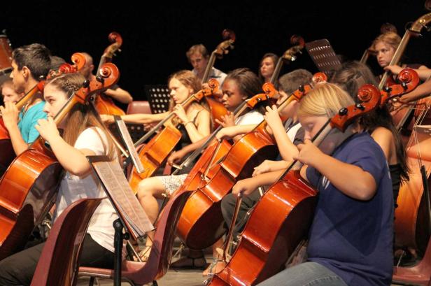 Ein Orchester mit jungen Cellisten spielt auf der Bühne.