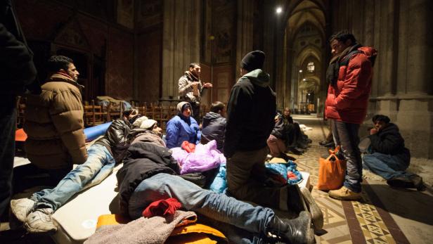 Die Flüchtlinge campierten in der Kirche Eine Gruppe von Menschen ruht in einem Kirchengebäude auf Matratzen und Schlafsäcken.
