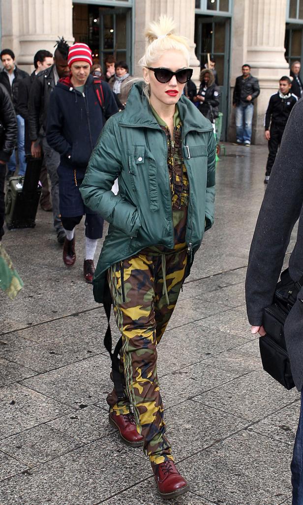 Gwen Stefani in Camouflage-Hosen und grüner Jacke geht auf der Straße.