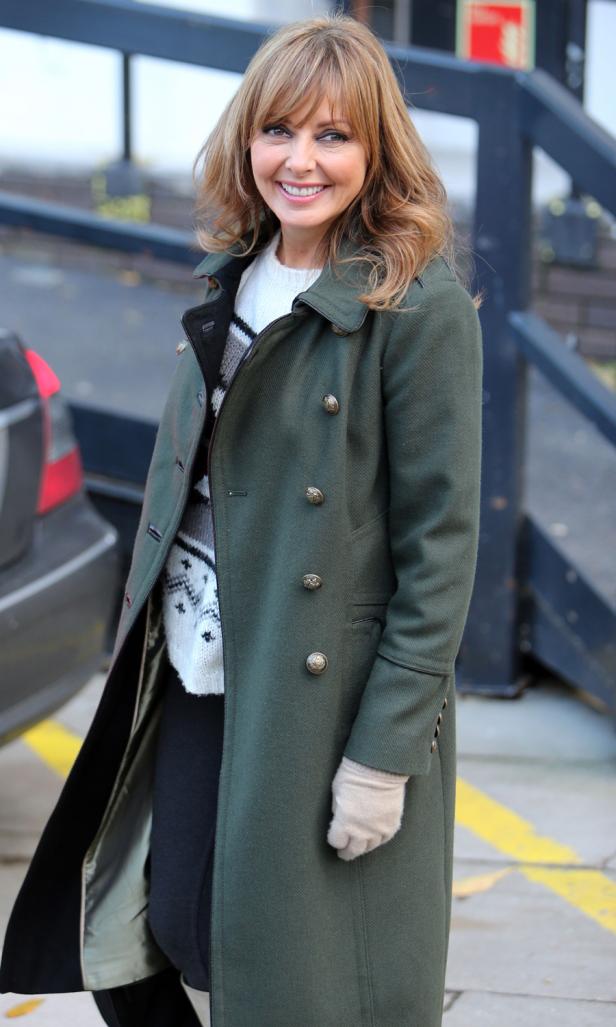 Carol Vorderman trägt einen grünen Mantel und beigefarbene Handschuhe.