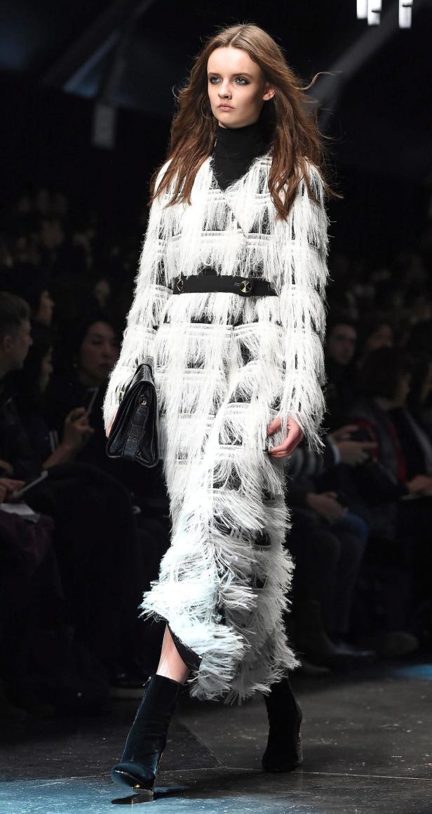 Eine Frau in einem langen, weißen Fransenkleid auf dem Laufsteg.