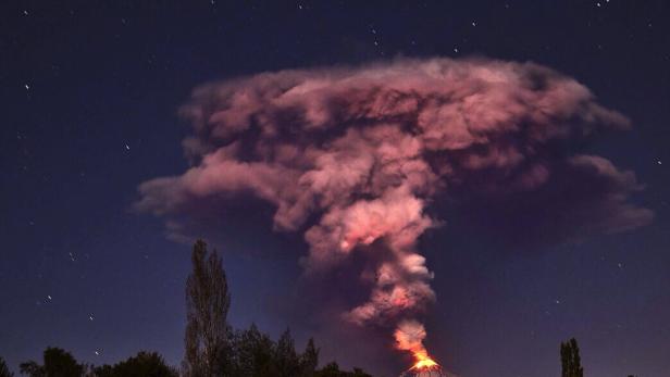 Ein Vulkan bricht nachts aus und speit Rauch und Lava in den Himmel.