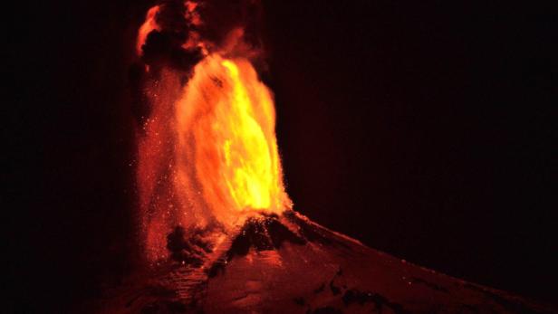 Ein Vulkan bricht nachts aus und speit Lava und Asche in den Himmel.