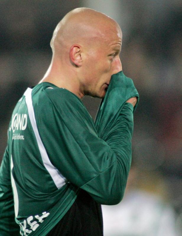 Ein Fußballspieler mit grünem Trikot wischt sich den Schweiß ab.